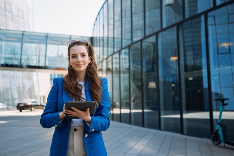 Successful woman real estate agent holding tablet and looking to camera. Business centre location. High quality photo