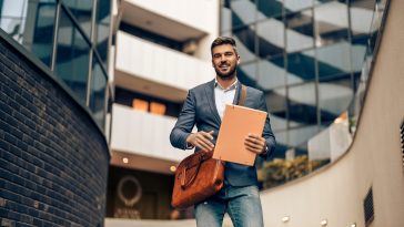 Handsome businessman in corporate suit walking with briefcase  in city.