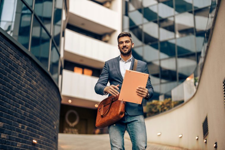 Handsome businessman in corporate suit walking with briefcase  in city.