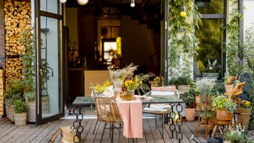 Beautifully decorated dining table with flowers on wooden terrace of country house