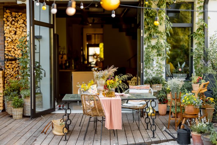 Beautifully decorated dining table with flowers on wooden terrace of country house