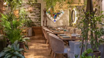 Eco architecture. Floral interior. Green cafe with plants. Urban environment concept. Ecology and green living in city. Modern restaurant covered green plant.