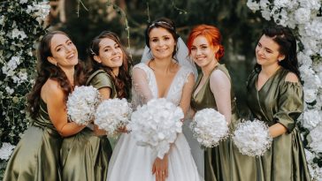 Bridesmaids smiling together with the bride. The bride and her fun friends celebrate the wedding after the ceremony in matching dresses. Bride and friends in nature