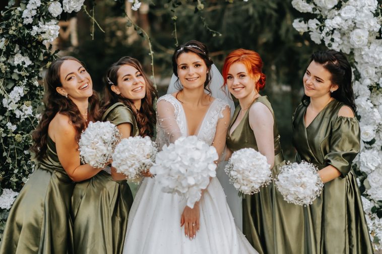 Bridesmaids smiling together with the bride. The bride and her fun friends celebrate the wedding after the ceremony in matching dresses. Bride and friends in nature