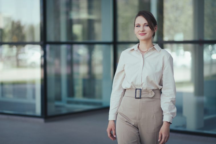 Business portrait of caucasian young woman in office or business style in clothes in beige tones against the backdrop of an office building.