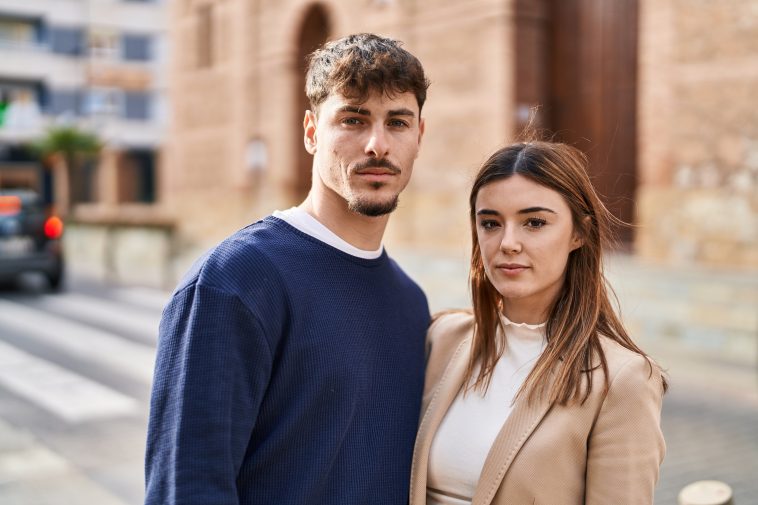 Mand and woman couple standing together with serious expression at street