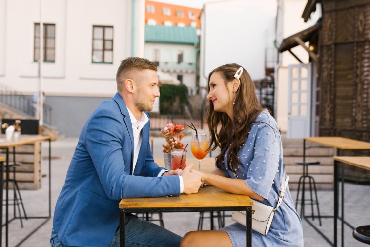 Beautiful couple in love is sitting at a table in an outdoor cafe on a date