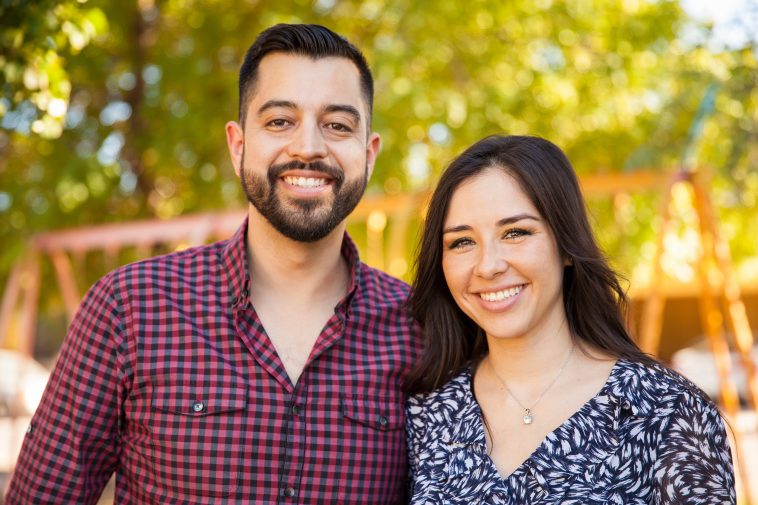 Attractive Latin young couple enjoying a sunny day outdoors and smiling