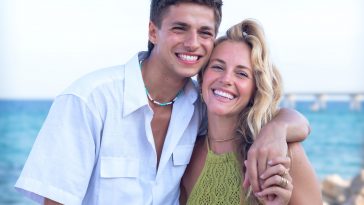 Smiling multiethnic woman and man enjoying vacation. Beautiful and cheerful couple of generation z pose for a photo with a mobile phone.