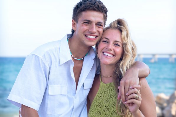 Smiling multiethnic woman and man enjoying vacation. Beautiful and cheerful couple of generation z pose for a photo with a mobile phone.