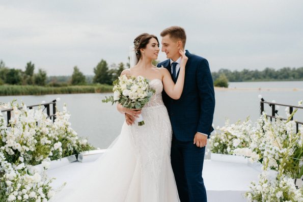 bride and groom against the backdrop of a yellow sunset on a pier near the river