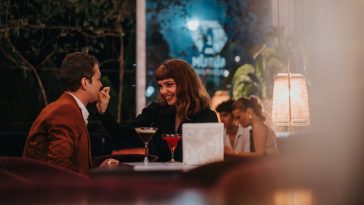 A loving couple shares a joyful moment during a romantic evening at a stylish restaurant with dim lighting and elegant ambiance.