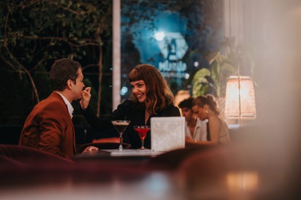 A loving couple shares a joyful moment during a romantic evening at a stylish restaurant with dim lighting and elegant ambiance.