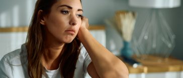 Young sad woman thinking of something in the bedroom. Copy space.