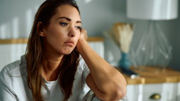 Young sad woman thinking of something in the bedroom. Copy space.