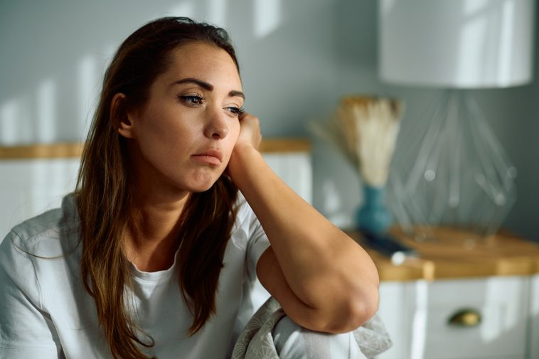 Young sad woman thinking of something in the bedroom. Copy space.