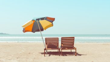 Vintage toned two beach chairs and umberella on empty tropical ocean beach at sunny day