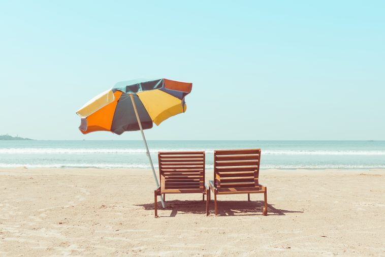 Vintage toned two beach chairs and umberella on empty tropical ocean beach at sunny day