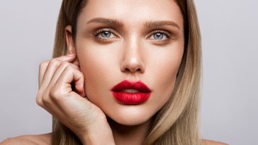 Beautiful young model with red lips and nude manicure