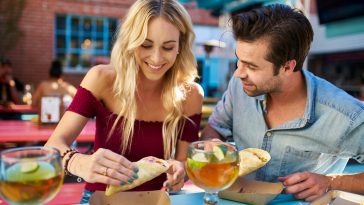 romantic couple eating street tacos at outdoor mexican restaurant