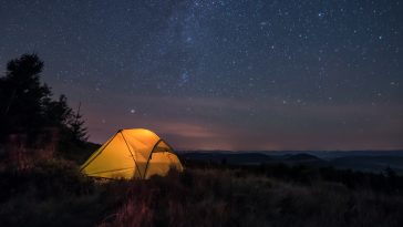 iluminated tent under stars in the mountains