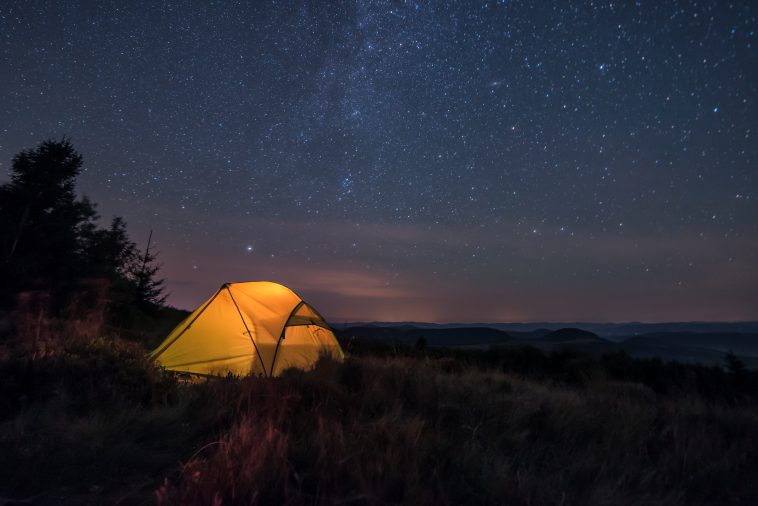 iluminated tent under stars in the mountains