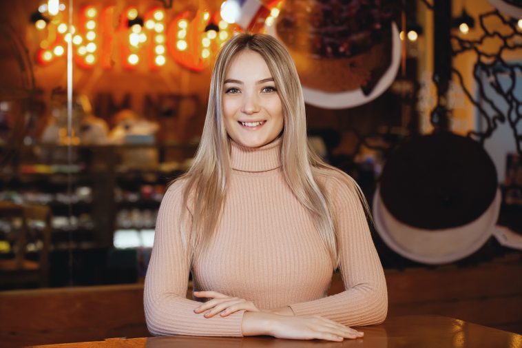 Portrait of a young pretty woman with pleasure posing at the camera in a cafe.