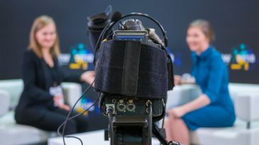 Television video camera recording interview in broadcast news studio. Blurred background. Media, production, TV and broadcast concept