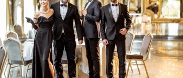 Portrait of an elegant people strictly dressed in black tie standing together at the luxury restaurant hall