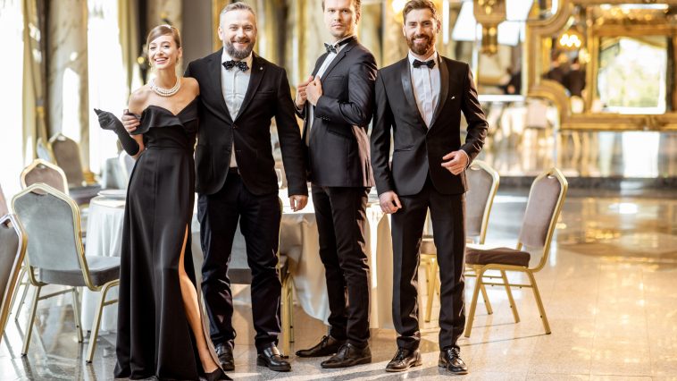 Portrait of an elegant people strictly dressed in black tie standing together at the luxury restaurant hall