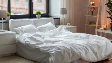 coziness and interior concept - cozy bedroom with white linen on bed