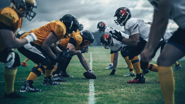 American Football Championship. Teams Ready: Professional Players, Aggressive Face-off, Ready for Pushing, Tackling. Competition Full of Brutal Energy, Power. Shot with Dramatic Light