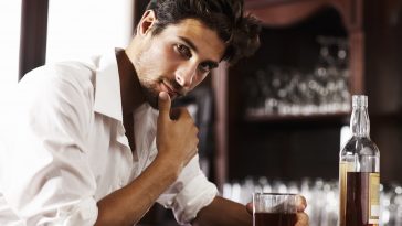 Young sophisticated man drinking whiskey alone at the bar