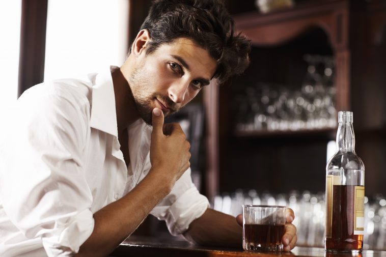 Young sophisticated man drinking whiskey alone at the bar