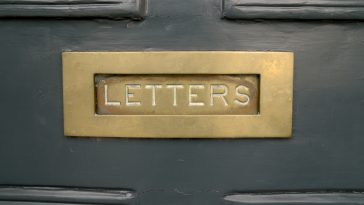 Painted solid dark green entrance door metal brass gold letter slot ornament inscription letters as a concept for postage mailings and old doors