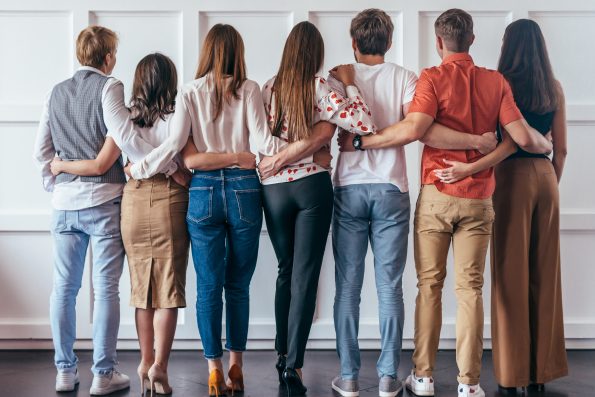 Group of young people hugging together Rear view.