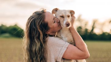 close up portrait of a happy woman hugging and kissing her dog