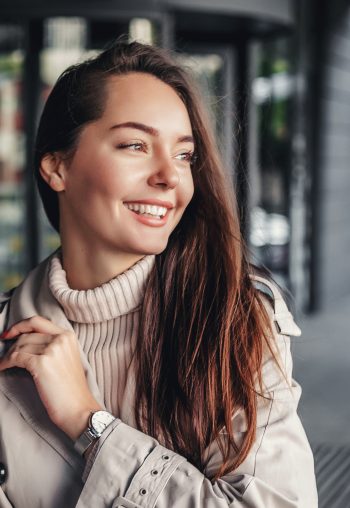 Portrait of a happy young woman against the background of an office building wearing a trench coat. copy space