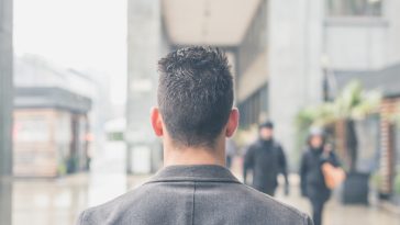 Back view of a young handsome man with short hair posing in the city streets