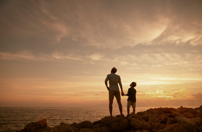 Father with son on the sea coast in sunset time