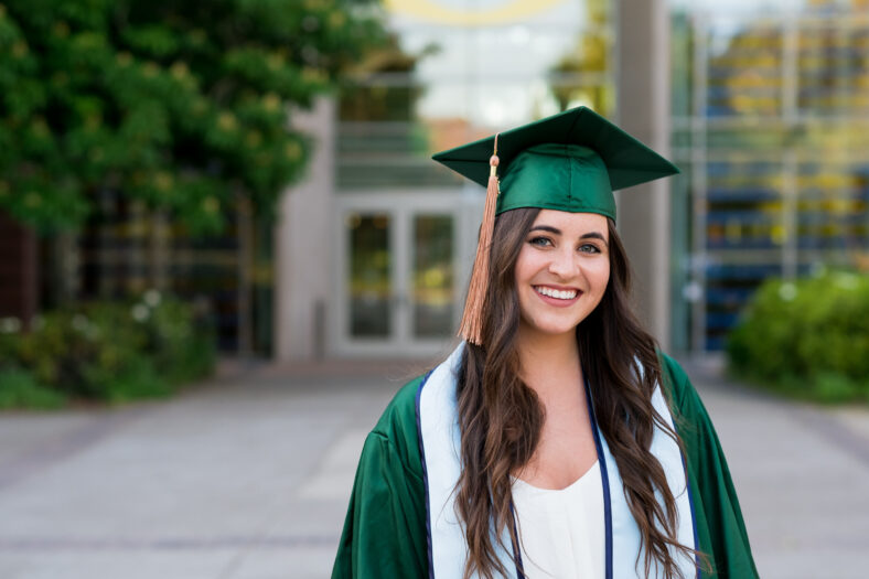 Pretty girl posing for a graduation photo on campus during her senior year of college right before graduation.