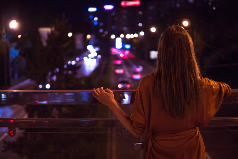 Young woman watching the view night city road from bridge.