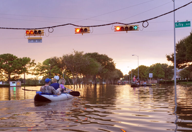 HOUSTON, USA - SEPTEMBER 2, 2017: Working traffic lights over flooded Houston streets and boats with people at sunset