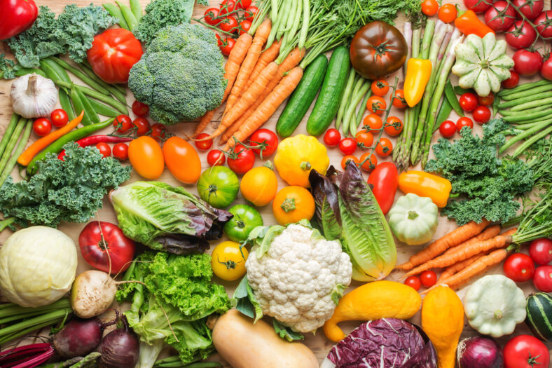 Assortment of fresh colorful organic vegetables on wooden pine table, healthy food background, top view, selective focus