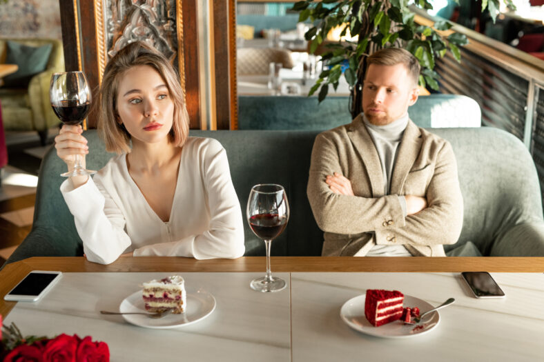 Pretty blond female with glass of red wine looking through window