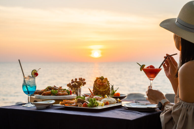 woman eating seafood at sunset time on the water