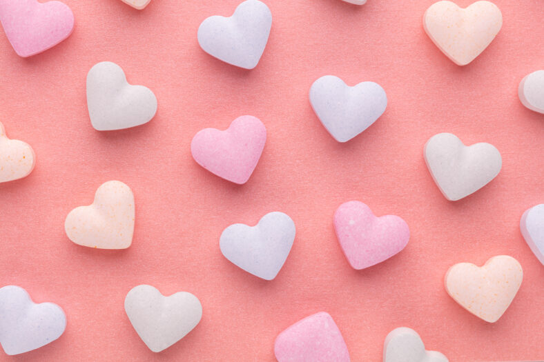 Valentine's Day background. Composition with candy hearts on pastel blue background. Valentines Day greating card. Flat lay, top view.