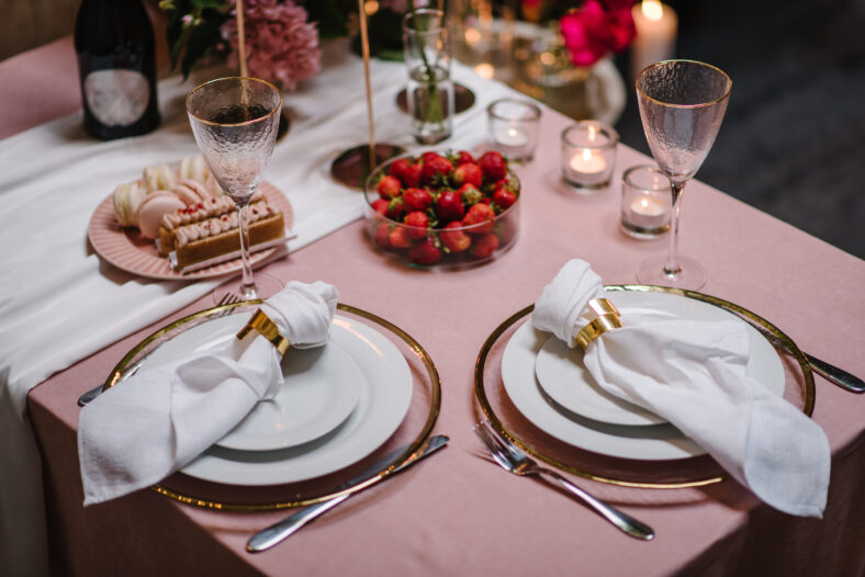 Candlelight dinner setup for couple on Valentines day. Decoration flowers, decor candles, details closeup. Luxury romantic date. Location for surprise marriage proposal. Table setting in restaurant.