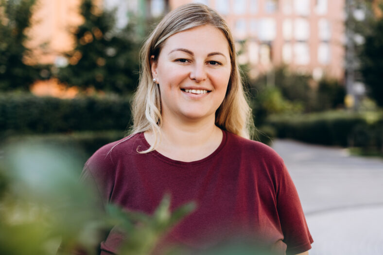 Portrait of smiling young plus size Caucasian woman posing at camera outside