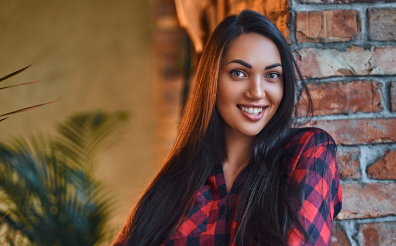 Portrait of a brunette hipster female dressed in a red fleece shirt in a room with loft interior.